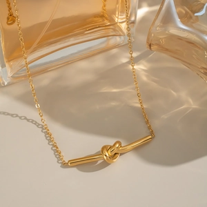 Collier avec pendentif nœud géométrique doré poli sur chaîne O et fond de luxe chaud