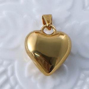 Close-up of polished 24k gold-plated heart pendant on elegant white lace background