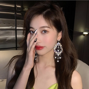 Close-up of luxury silver drop earrings with colorful rhinestones on fashion model