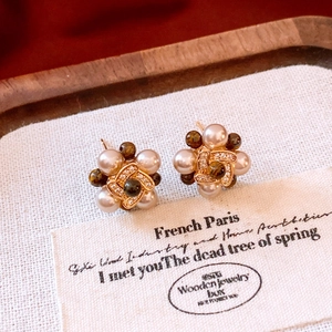 Detail of 18k gold plated flower stud earrings with pearls on a wooden jewelry display