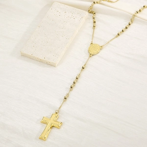 Detail of gold beaded rosary necklace with cross and medallion on white fabric