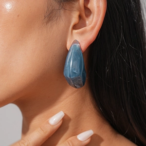 Macro view of blue marble resin earring with irregular geometric texture on model ear