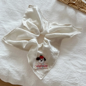 Close-up of a white satin hair scrunchie with cute puppy embroidery and brand woven label