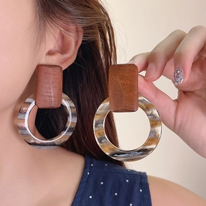 Close-up of retro wooden pendant earrings with large marble-patterned resin hoops