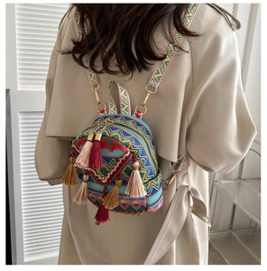 Detail of embroidered ethnic style backpack with tassels and colorful woven straps