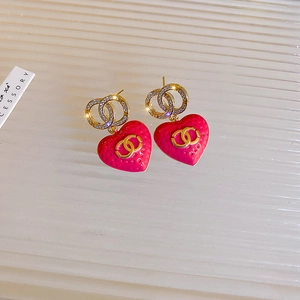 Macro shot of pink enamel heart earrings with golden logo and sparkling cubic zirconia