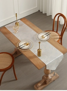 Detail of cream white table runner with jacquard pattern and elegant tassels on wood table