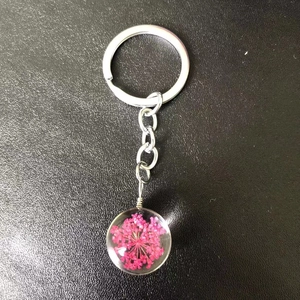 Close-up of a glass keychain with dried pink flowers and a silver alloy chain link