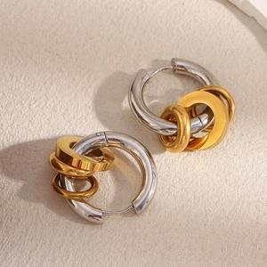 Détail macro de boucles d'oreilles géométriques triple anneau en or et argent sur papier