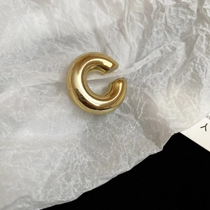Vue détaillée d'une boucle d'oreille dorée torsadée sur un fond de papier blanc texturé