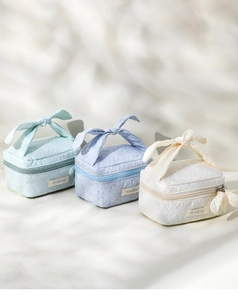Three bow-knot floral makeup bags in mint, blue and white on a sunlit background