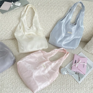 Detailed close-up of glossy satin tote bags in cream, blue, pink and grey colors