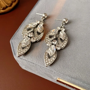 Macro shot of silver tassel earrings with marquise diamonds on a gray velvet box