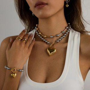 Close-up of gold and silver beaded jewelry set featuring heart pendants and toggle clasps