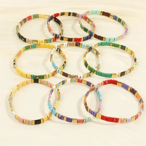 Colorful Bohemian Tila bead stretch bracelets with gold spacers on beige silk background
