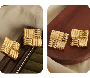 Detailed view of square gold-plated earrings with cross-woven texture on velvet and wood