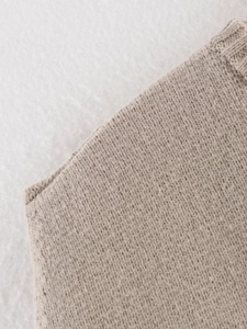 Macro view of oatmeal knitted vest showing soft rib-stitched edges and fine wool texture