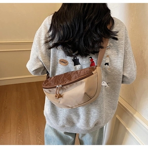 Rear view of a two-tone nylon crescent bag with adjustable wide strap on a female model