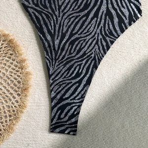 Detail shot of zebra print gold-stamping swimsuit fabric on a textured beige background