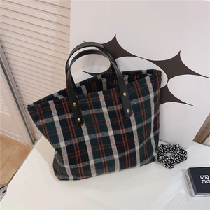 Detail of vintage plaid canvas tote showing thick tweed texture and rivet handles