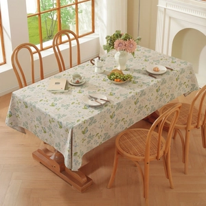 Pastel floral linen tablecloth with tassels on a wooden dining table in a cozy home setting