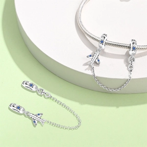 Detailed view of silver airplane charm with blue zircon stones on a charm bracelet