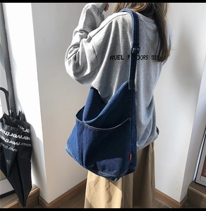 Close-up of large deep blue denim tote bag with visible texture and side orange label