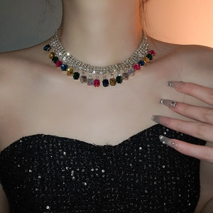 Gros plan d'un collier à pompons argenté serti de cristaux carrés multicolores sur un mannequin