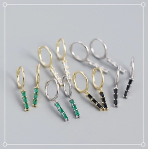 Macro shot of geometric rectangular zircon earrings in emerald, white, and black stones
