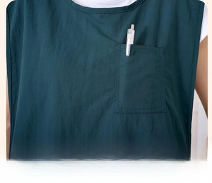 Close-up of practical chest pocket on dark green waterproof work apron vest with a pen