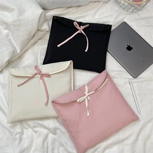 Dettaglio di custodie trapuntate per laptop con fiocchi in rosa, bianco e nero