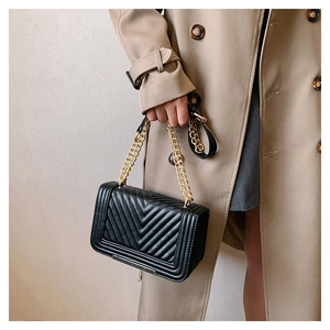 Close-up of black crossbody bag with V-quilted faux leather and chunky gold chain strap