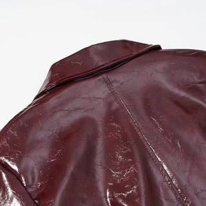 Dettaglio del colletto della giacca in pelle verniciata rosso vino con cuciture