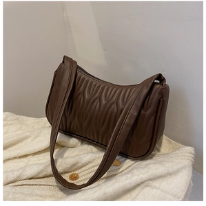 Deep brown quilted underarm bag in faux leather on a beige cardigan