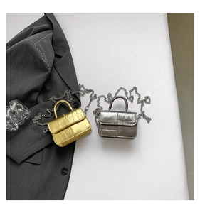 Detail of silver and gold mini chain bags with crocodile texture on a blazer