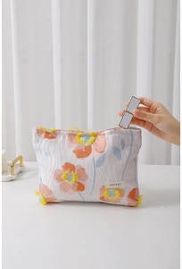 Detailed view of floral jacquard makeup bag with orange flower patterns and label