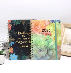 Close-up of 2026 weekly planner with gold coil binding and floral pattern cover