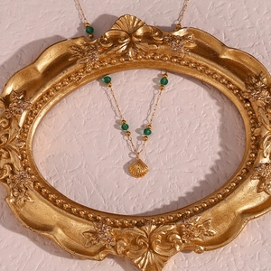 Detail of shell pendant necklace with green beads inside a vintage golden frame