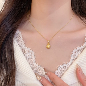Detail of a gold lucky bag pendant necklace with white zircons on a model's neck
