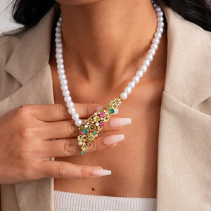 Close-up of vintage pearl necklace featuring a floral gold pendant with colorful gems