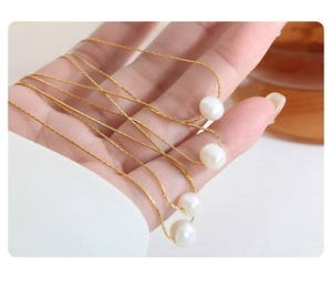 Detailed close-up of natural white freshwater pearls on a delicate gold titanium steel chain