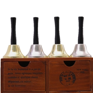 Set of 4 gold and silver Christmas hand bells with black handles on a vintage wooden base