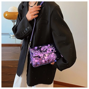 Close-up of sparkling purple sequin crossbody bag styled on a black blazer