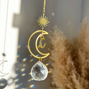Detail of hanging sun catcher with gold crescent moon and faceted crystal ball reflecting light