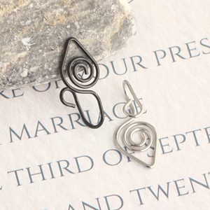 Detail of matte black and silver spiral faux nose rings on a natural stone surface