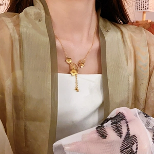 Detailed view of a gold-plated floral tassel necklace on a model in traditional style