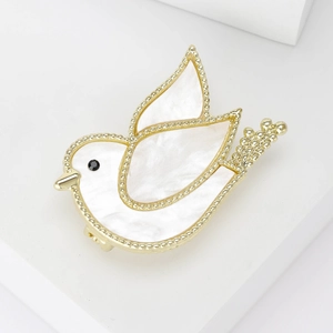 Detail of peace dove brooch with golden metal finish and white shell inlay detail