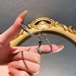 Detailed view of an irregular wavy silver ring with polished finish worn on a finger