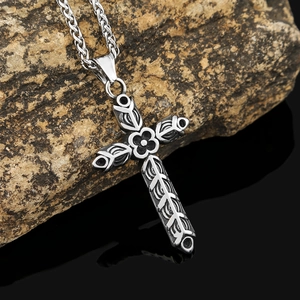 Collier avec pendentif croix à fleurs en acier inoxydable poli sur fond de roche