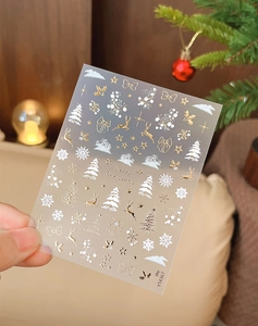 Détails d'autocollants à ongles de Noël avec flocons dorés et rennes sur fond festif